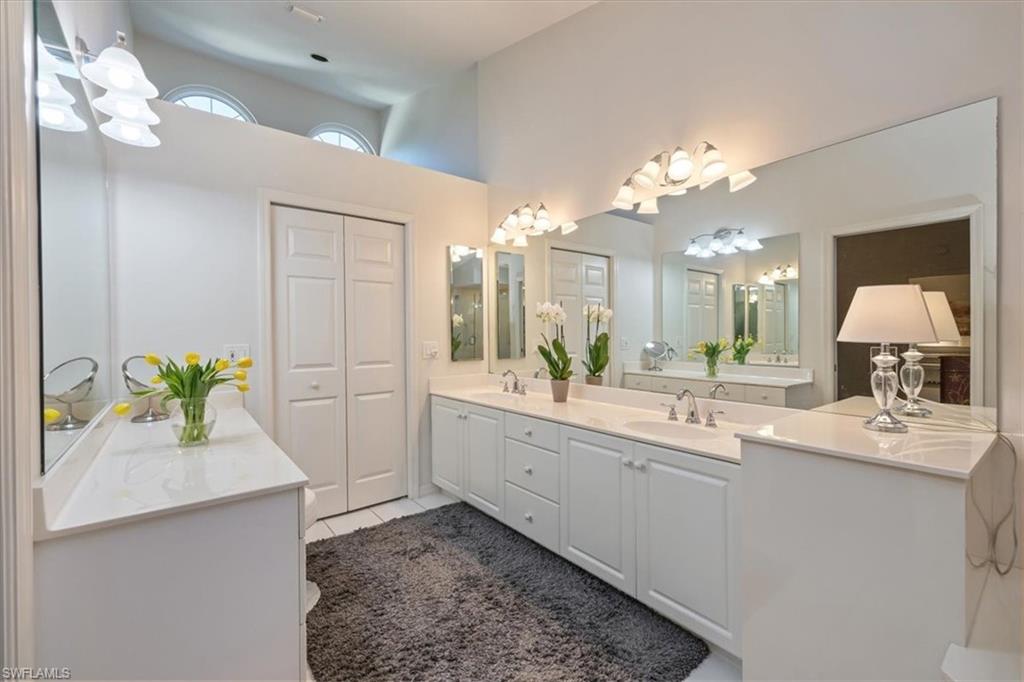 203 Via Perignon, Unit 24 Naples, FL 34119 - Photo 19 of 24 The primary bath offers dual vanities, a luxurious soaking tub, and a separate glass-enclosed shower, all opening to a spacious walk-in closet illuminated by a large window and abundant natural light.