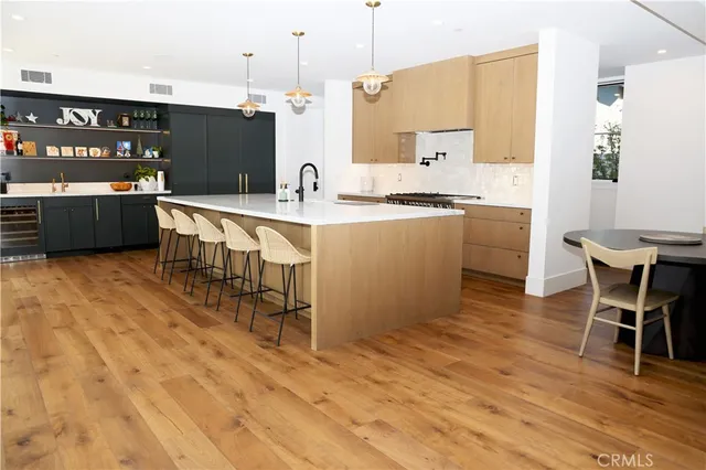 a large kitchen with stainless steel appliances kitchen island granite countertop a table chairs and a refrigerator