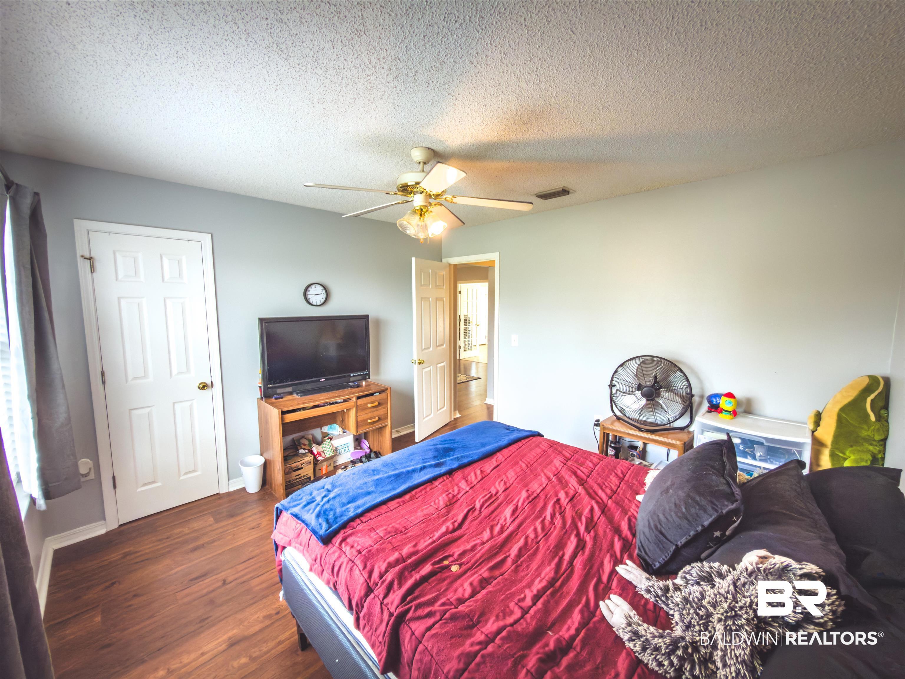 129 Pennbrooke Loop Foley, AL 36535 - Photo 13 of 44 Bedroom with dark wood-style flooring, a textured ceiling, and ceiling fan