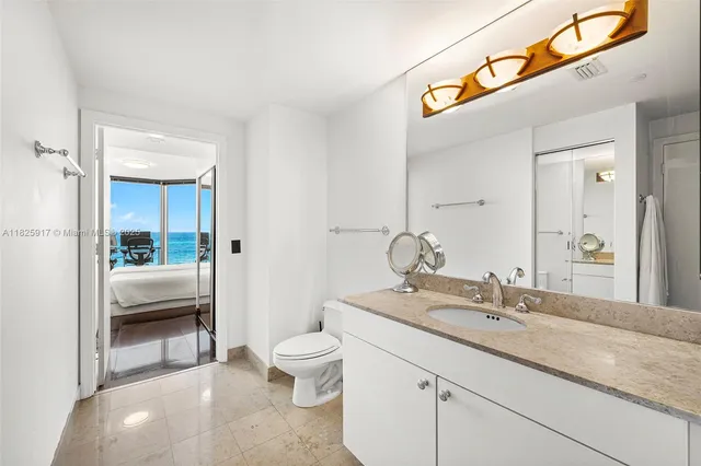 a spacious bathroom with a granite countertop sink a toilet and a mirror