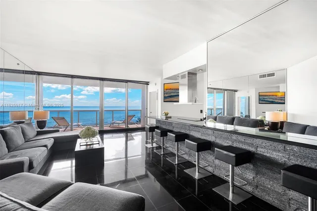 a large living room with stainless steel appliances granite countertop a couch and a large window