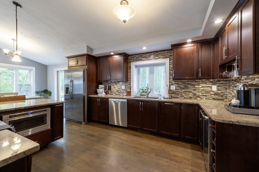 357 Ledge Road Seekonk, MA 02771 - Photo 6 of 42 a kitchen with kitchen island granite countertop wooden cabinets a sink a stove and a refrigerator