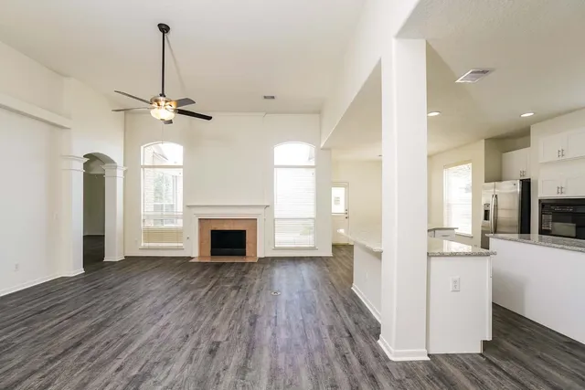 a view of a hallway with wooden floor and a kitchen