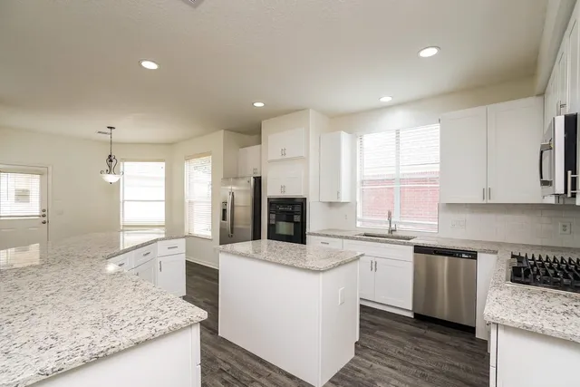 a kitchen with granite countertop a sink a counter top space stainless steel appliances and cabinets
