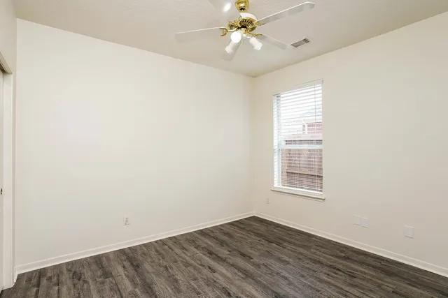 an empty room with wooden floor closet and windows