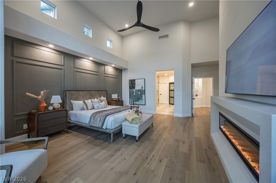 8800 Lusso Las Vegas, NV 89134 - Photo 40 of 85 Bedroom with a glass covered fireplace, recessed lighting, a high ceiling, light wood-style flooring, and ceiling fan