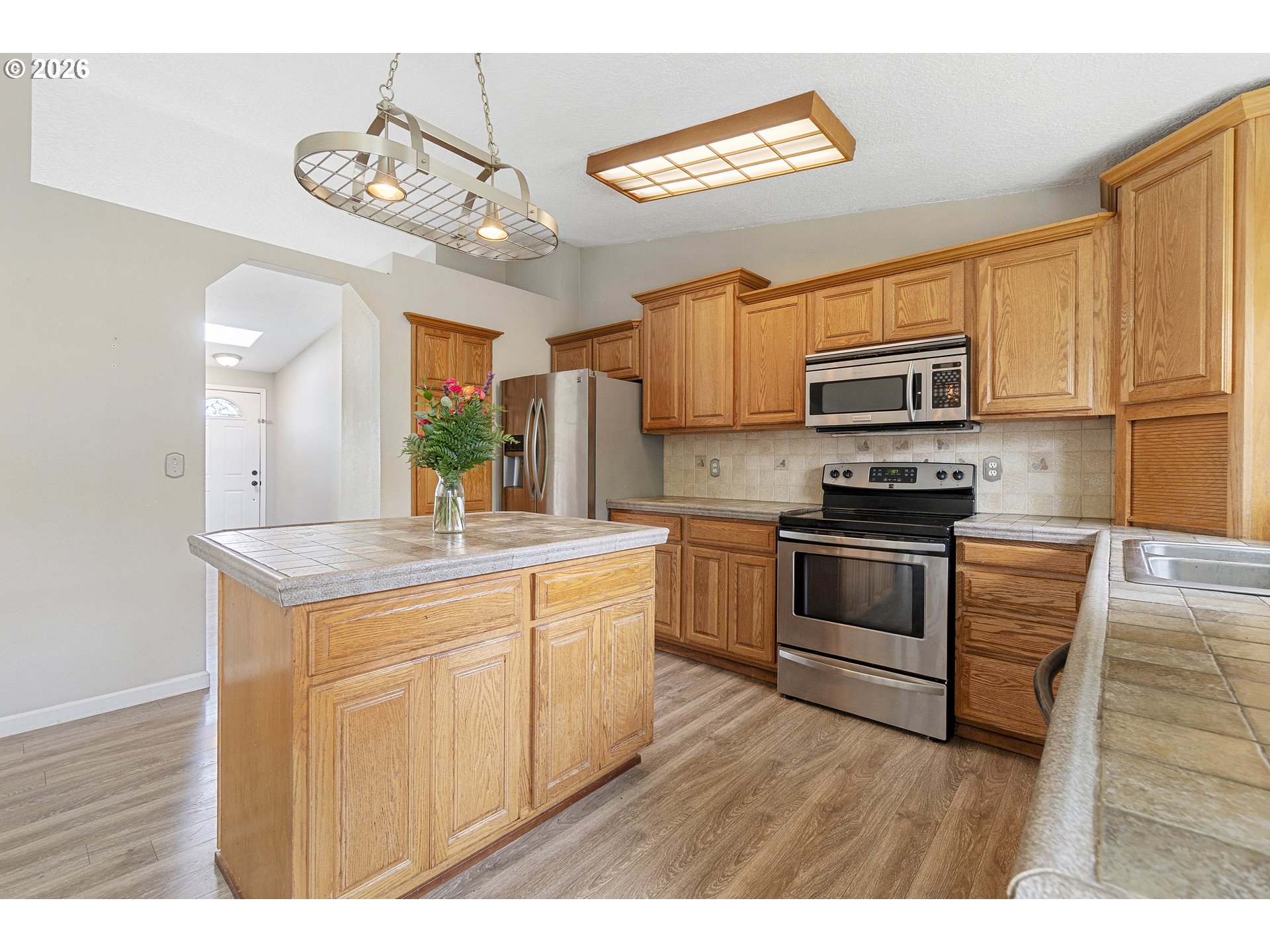 6749 Southwest 174th Place Beaverton, OR 97007 - Photo 13 of 39 a kitchen with kitchen island granite countertop a stove cabinets and wooden floor