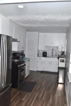 a kitchen with stainless steel appliances granite countertop a stove a refrigerator and a white cabinets