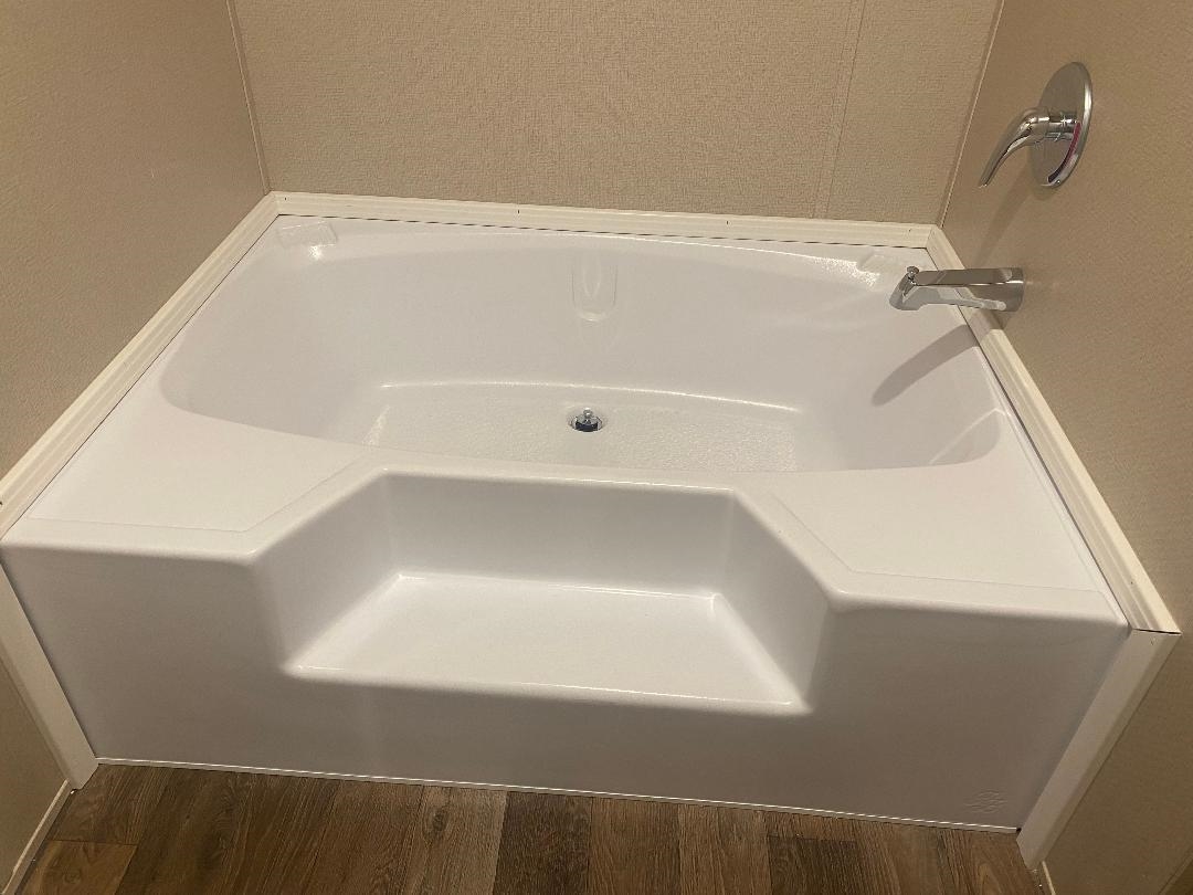 106 Simmons Road Munford, TN 38058 - Photo 14 of 30 White corner bathtub with integrated steps, chrome fixtures, and wood-finish flooring