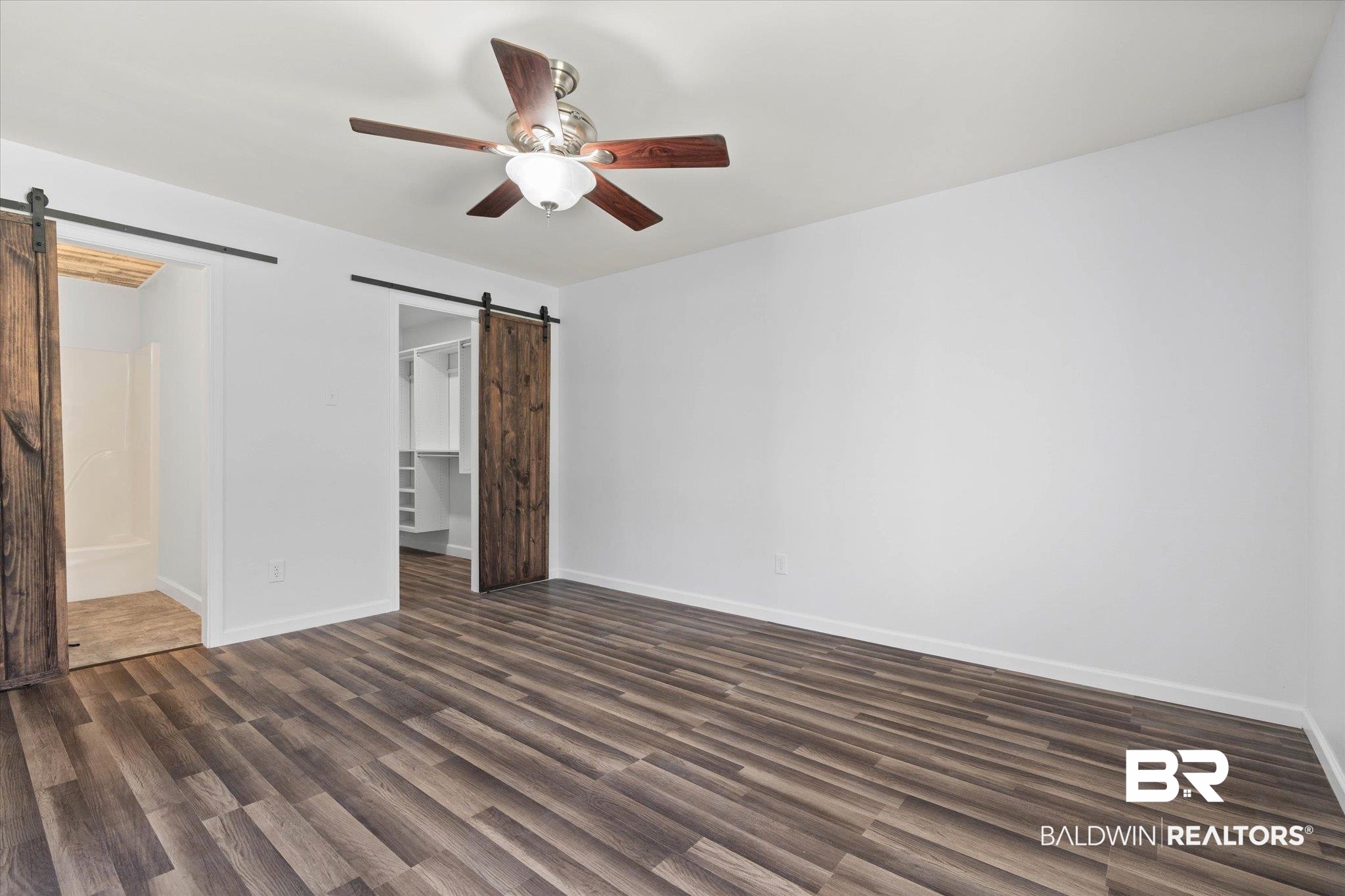 123 Richmond Road Daphne, AL 36526 - Photo 11 of 35 Unfurnished bedroom with a barn door, dark wood-style flooring, a spacious closet, a closet, and ceiling fan