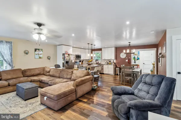 a living room with furniture kitchen view and a chandelier