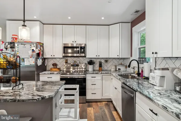 a kitchen with kitchen island granite countertop white cabinets and white appliances