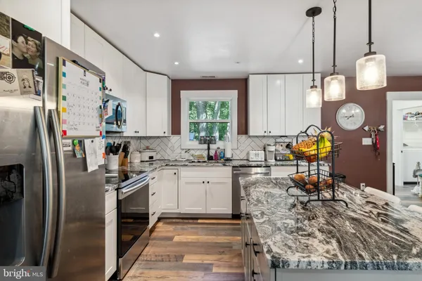 a kitchen with stainless steel appliances granite countertop a sink and a refrigerator