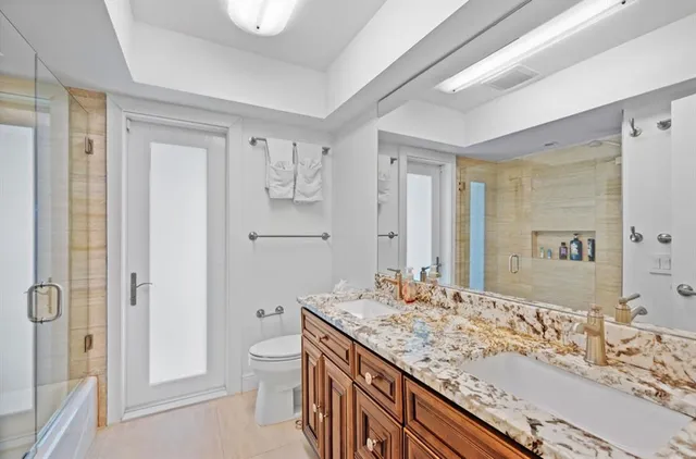 a bathroom with a granite countertop sink a toilet and shower