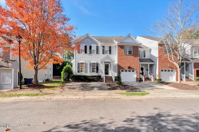 a view of a white house with a large tree in front of it