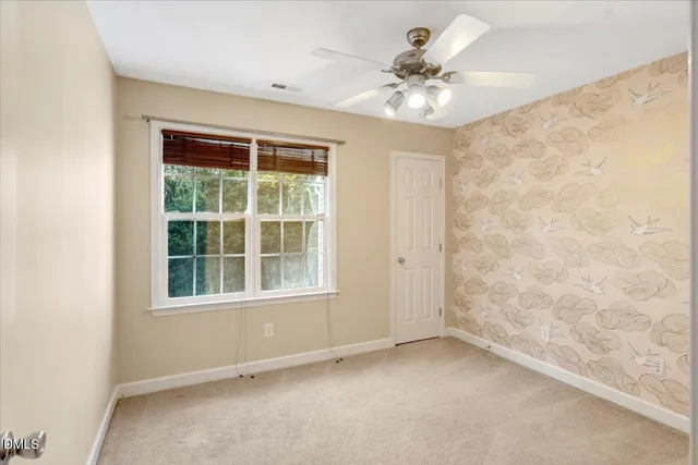 an empty room with windows and chandelier fan