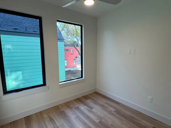 a view of an empty room with a window and wooden floor