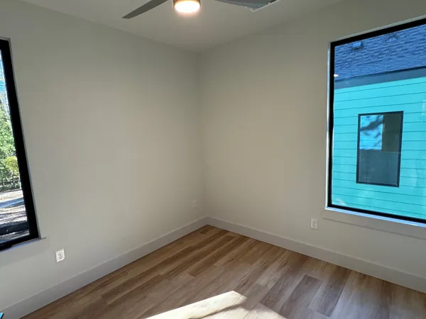 a view of empty room with wooden floor and fan