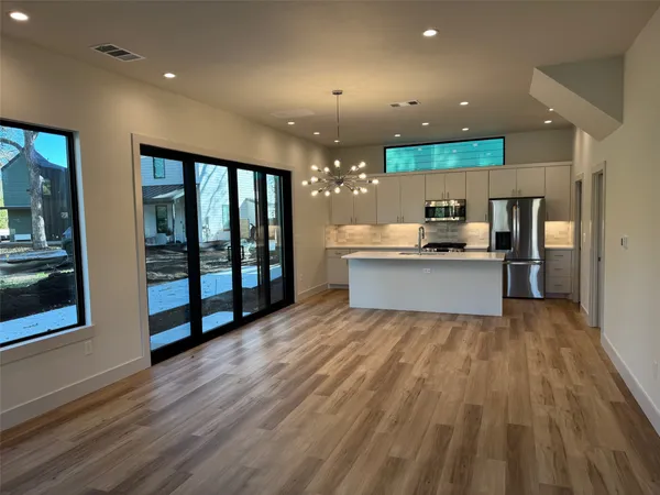 a view of kitchen with stainless steel appliances kitchen island wooden floor and large window