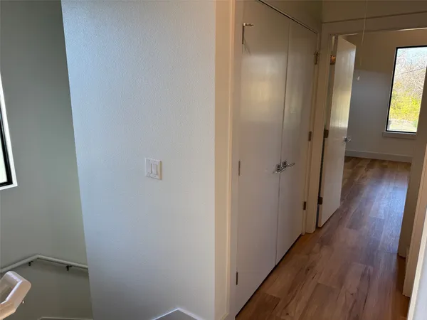 a view of a hallway with wooden floor and a bathroom