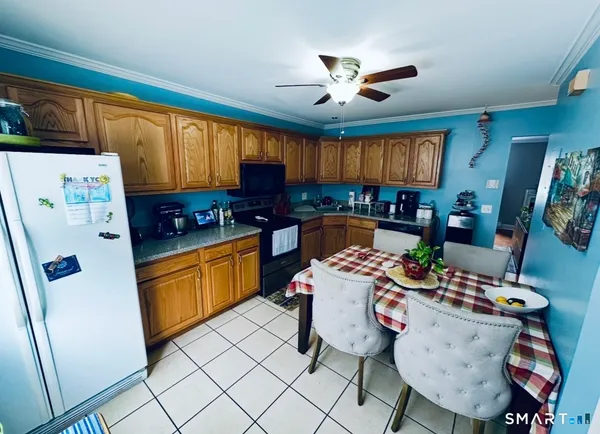a very nice looking open kitchen with stainless steel appliances granite countertop a refrigerator a sink a stove a dining table and chairs with wooden floor