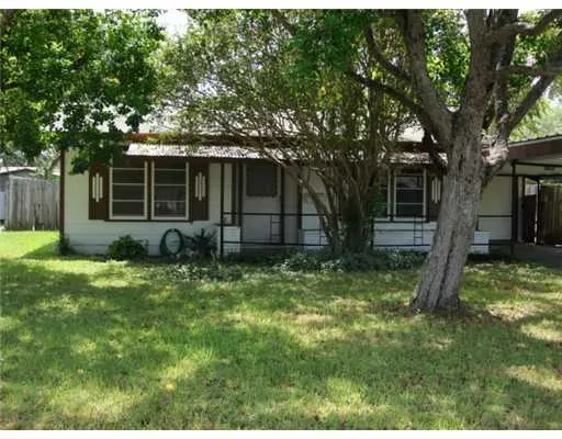 a backyard of a house with plants and large tree