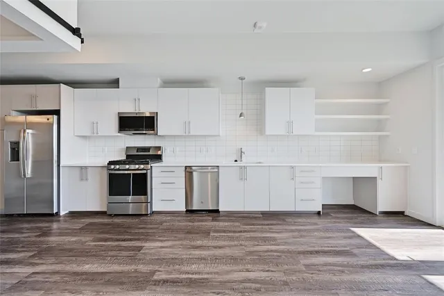 a kitchen with granite countertop a stove a sink and a refrigerator
