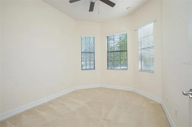 an empty room with windows and chandelier fan