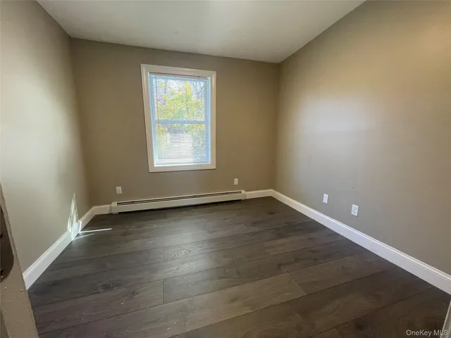 an empty room with wooden floor and window
