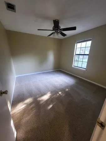an empty room with windows and ceiling fan