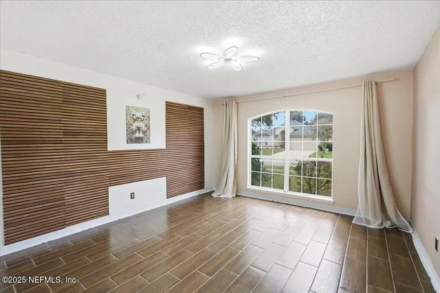 a view of empty room with wooden floor and fan