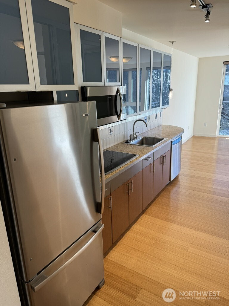 3104 Western Avenue, Unit 215 Seattle, WA 98121 - Photo 7 of 18 a kitchen with stainless steel appliances a refrigerator a sink a stove and white cabinets