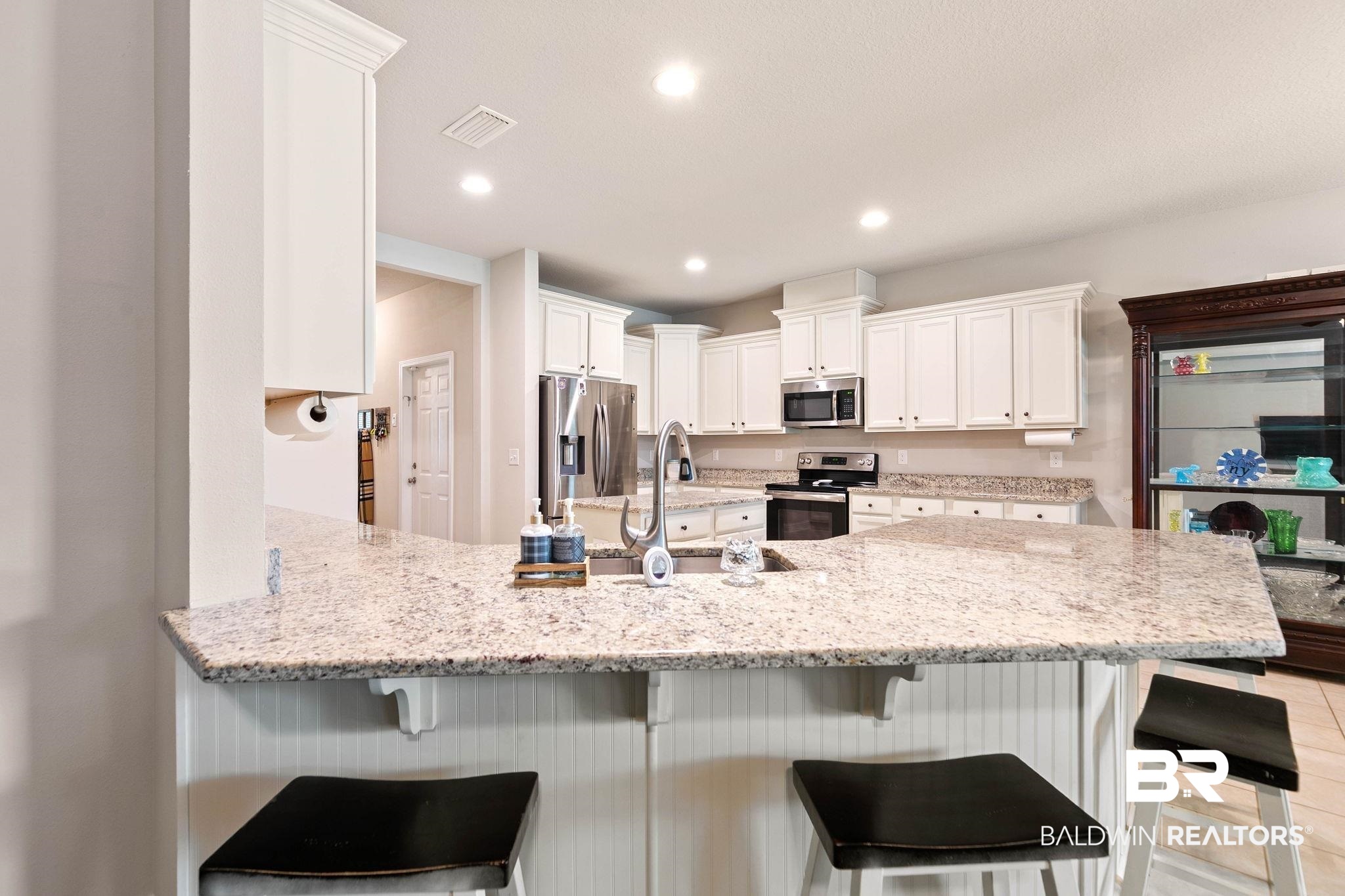 12750 B Jenkins Pit Road Daphne, AL 36527 - Photo 21 of 89 Kitchen featuring a kitchen breakfast bar, white cabinetry, a peninsula, stainless steel appliances, and light stone countertops