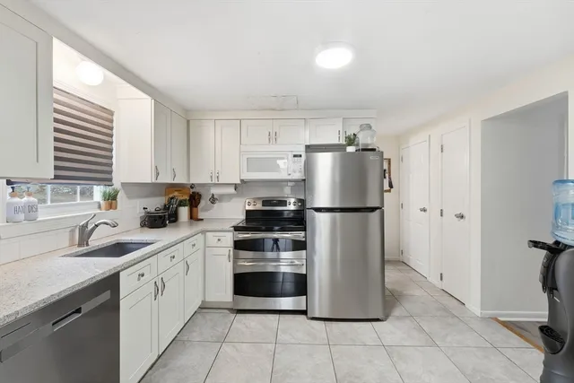 a kitchen with a refrigerator and white cabinets