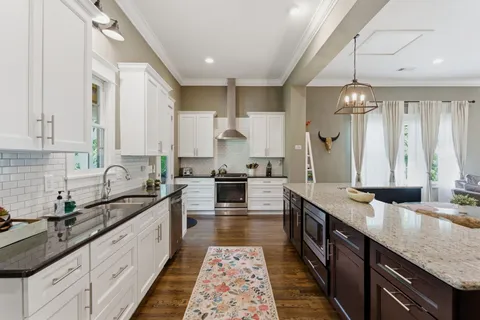 a large kitchen with granite countertop a sink and cabinets