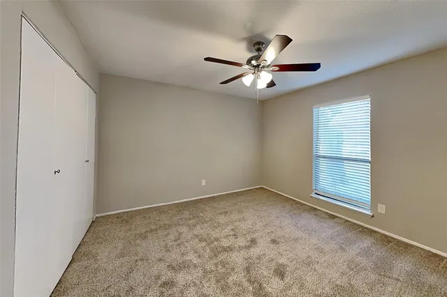 an empty room with ceiling fan and window