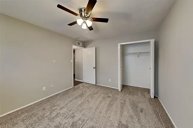 an empty room with a chandelier fan and windows