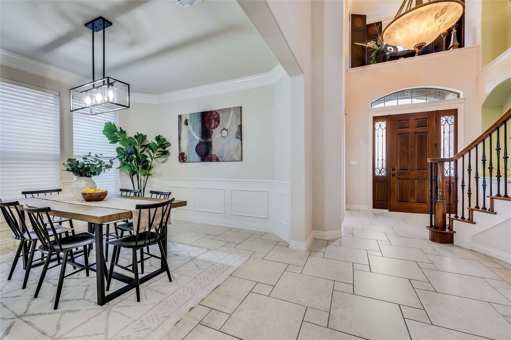 408 Ridgetop Bend Cedar Park, TX 78613 - Photo 16 of 40 A grand entryway features a curved staircase and an elegant wood door, opening to a sun-lit dining area with contemporary lighting.