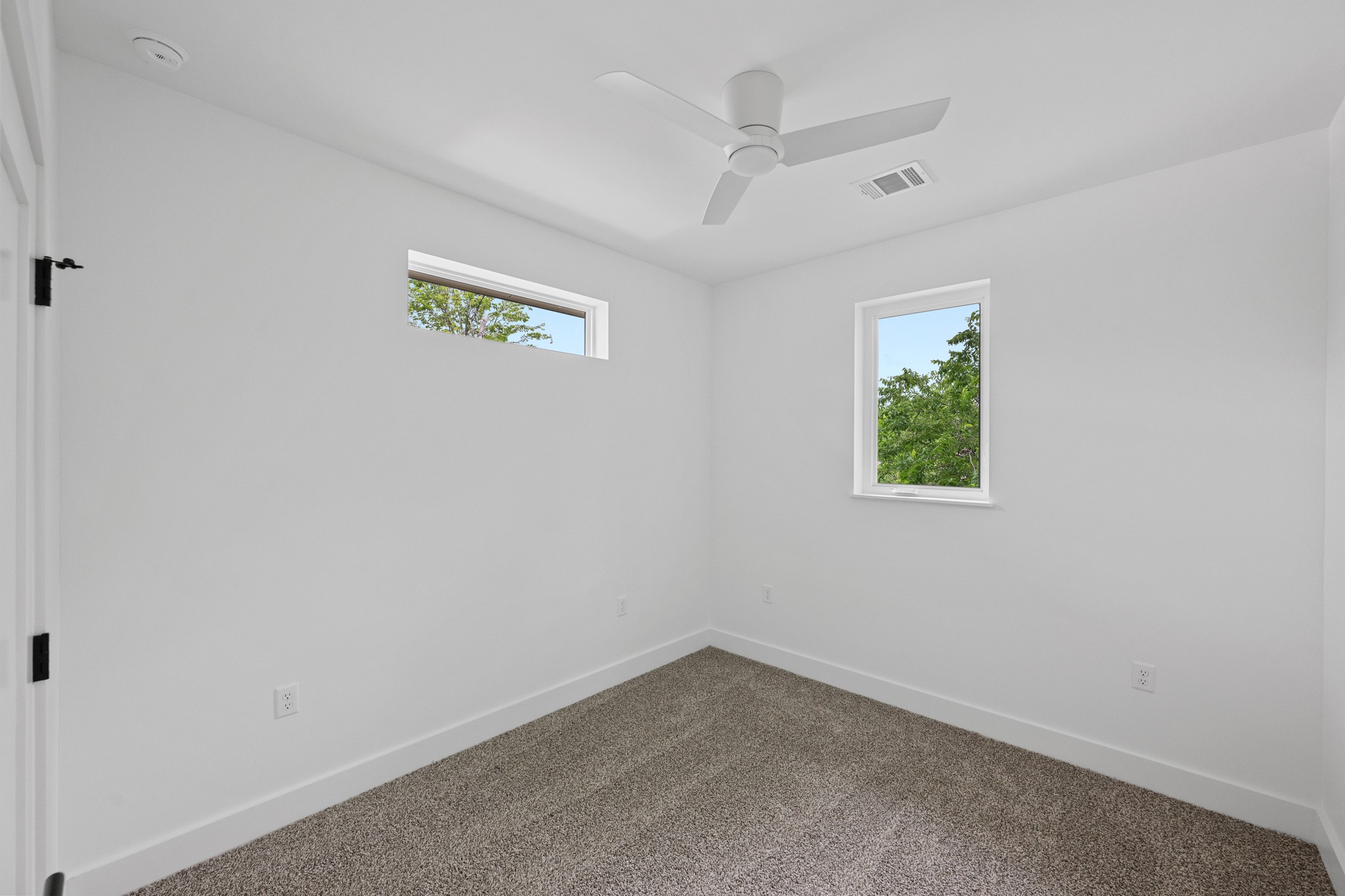 3614 Abbate Circle, Unit A Austin, TX 78721 - Photo 18 of 29 The room features a neutral color palette, with white walls and a grey carpeted floor, providing a versatile foundation for personalization