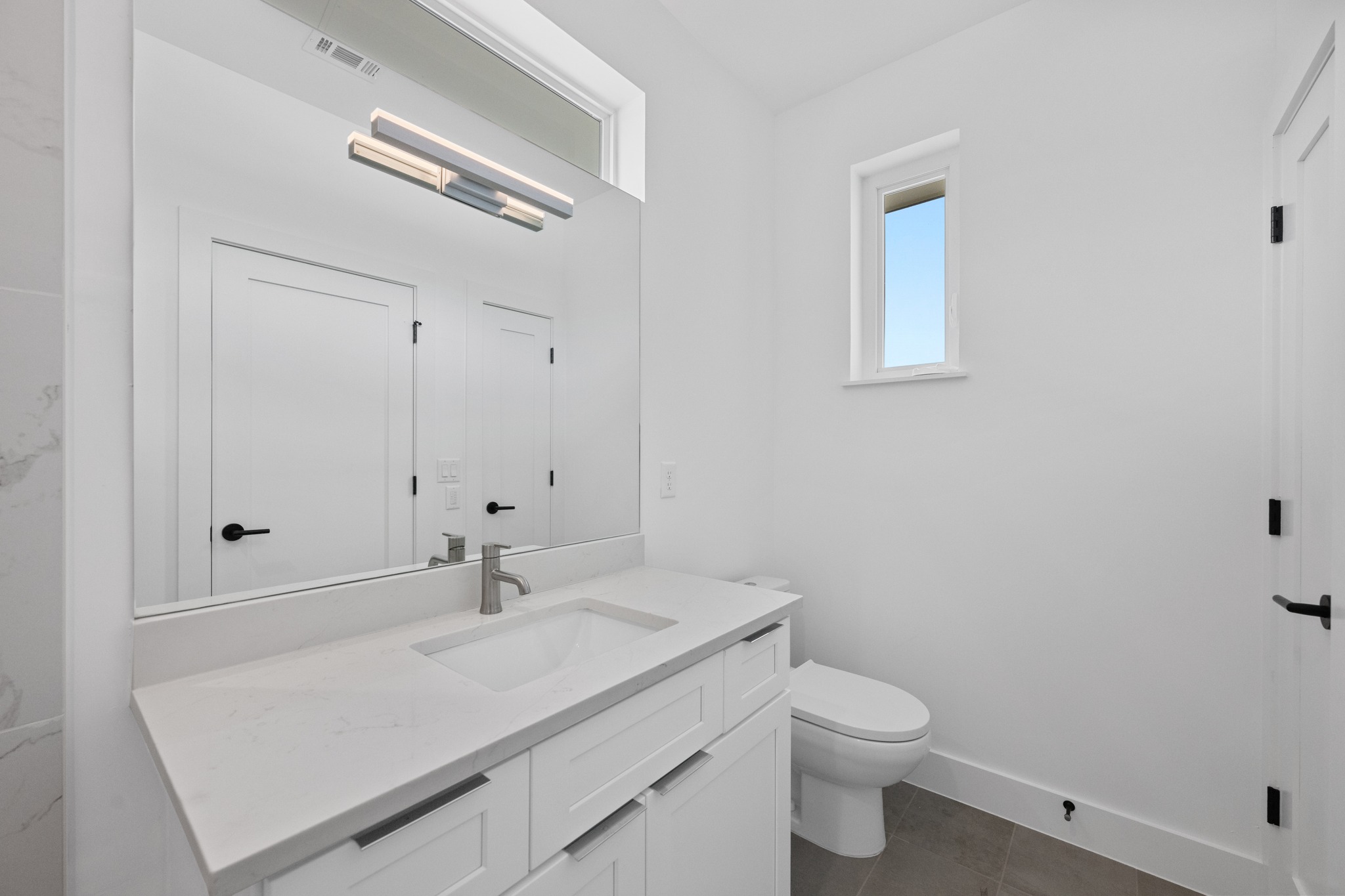 3614 Abbate Circle, Unit A Austin, TX 78721 - Photo 20 of 29 Bathroom featuring a vanity with a white countertop, an undermount sink, and a large mirror with contemporary lighting