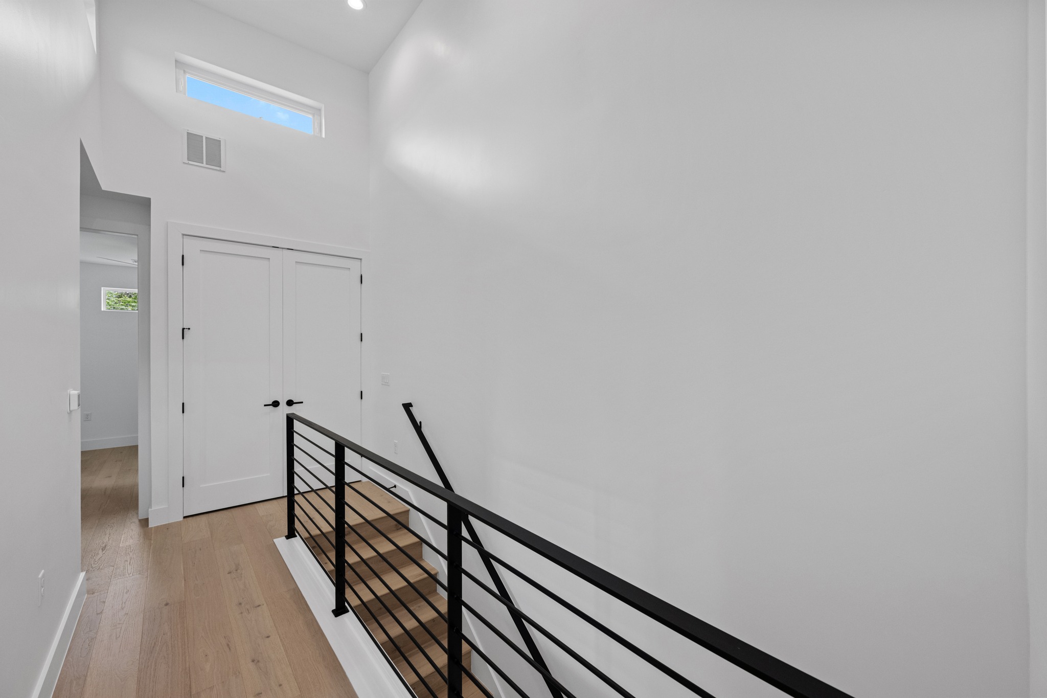 3614 Abbate Circle, Unit A Austin, TX 78721 - Photo 23 of 29 Bright interior space featuring light wood floors, a modern black metal staircase railing, and a window providing natural light