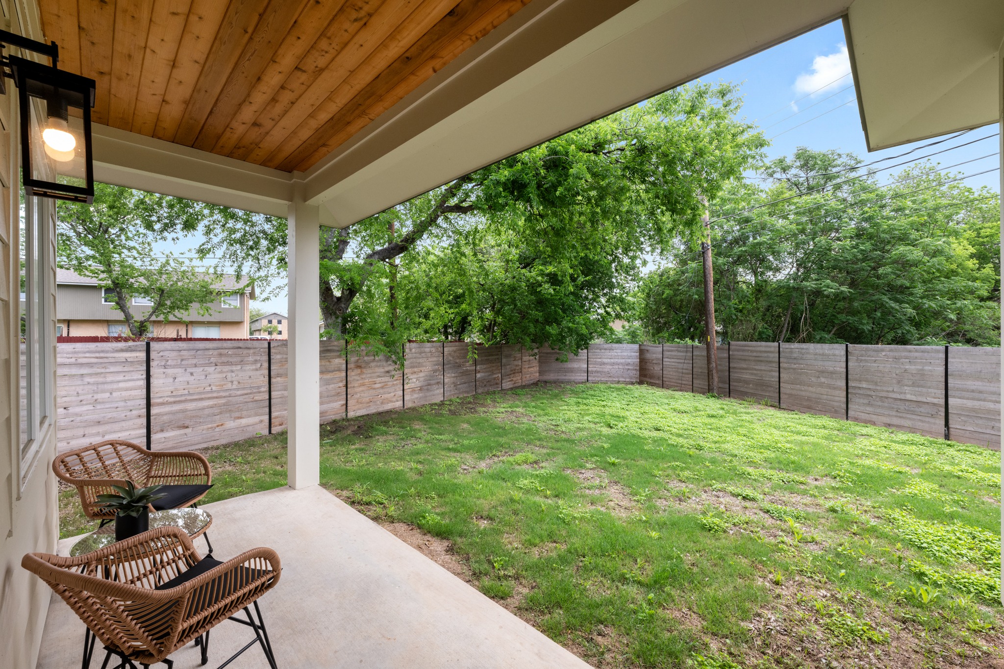 3614 Abbate Circle, Unit A Austin, TX 78721 - Photo 24 of 29 The property features a covered patio with a wood-paneled ceiling and an outdoor light fixture, overlooking a fenced yard with a lawn