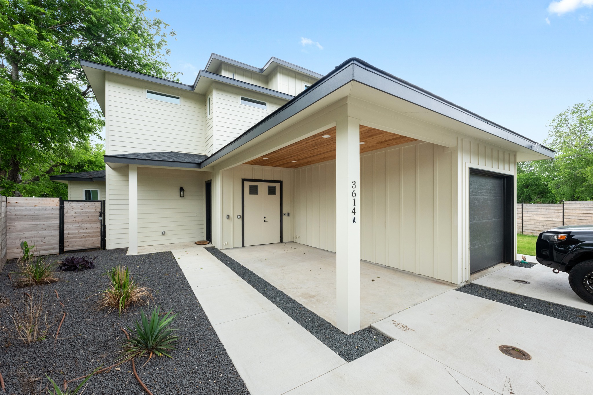 3614 Abbate Circle, Unit A Austin, TX 78721 - Photo 29 of 29 The property features a modern exterior with light-colored siding, a covered entry with a wooden ceiling, and an integrated garage with a black door
