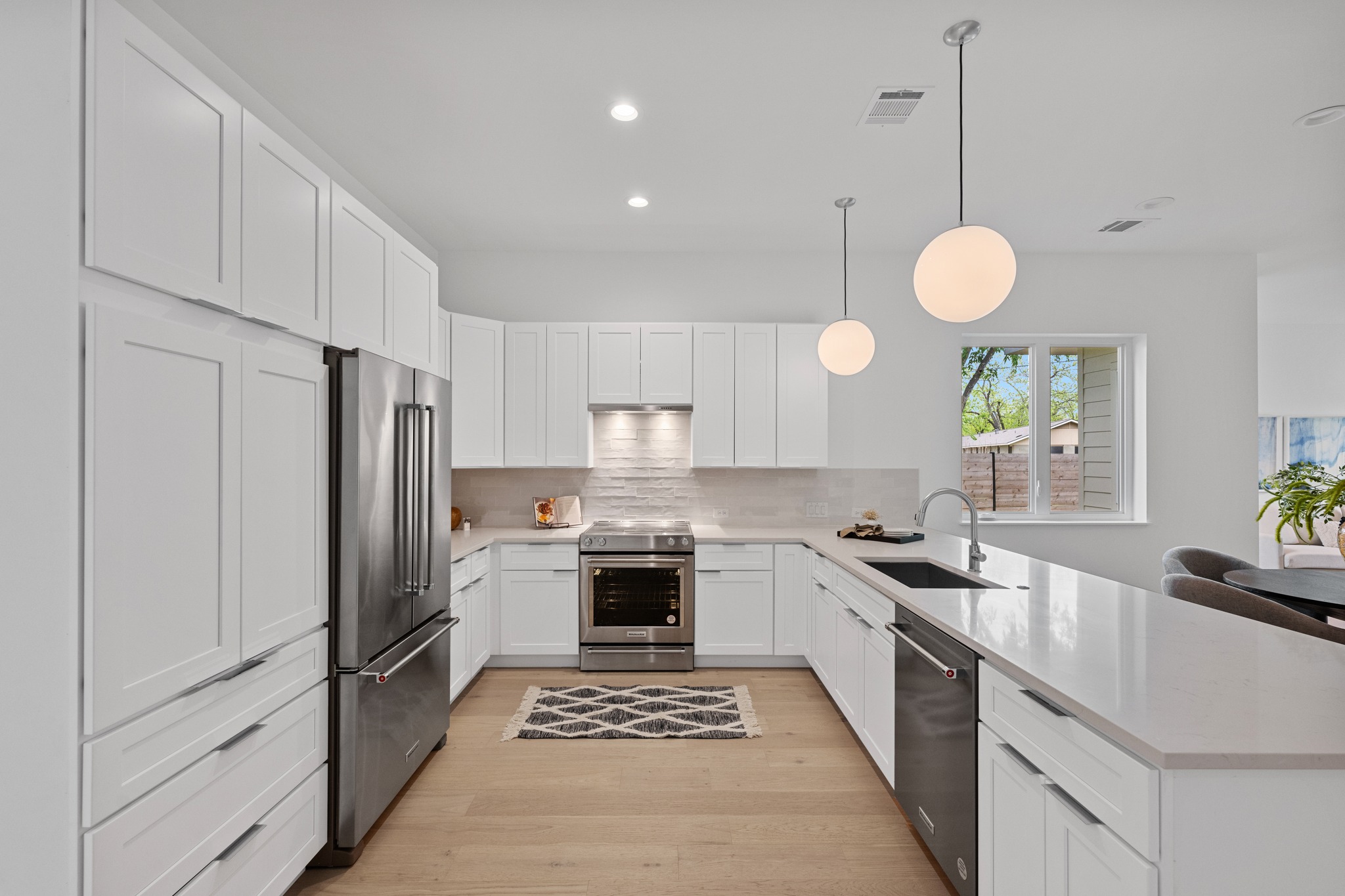 3614 Abbate Circle, Unit A Austin, TX 78721 - Photo 6 of 29 Modern kitchen featuring light wood flooring, white cabinetry, stainless steel appliances, and a light-colored countertop