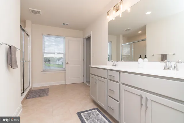 a spacious bathroom with a double vanity sink a mirror and a shower
