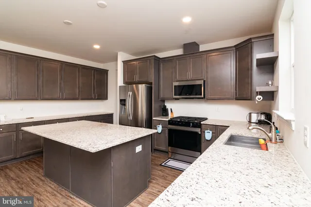a kitchen with stainless steel appliances granite countertop a sink refrigerator and cabinets