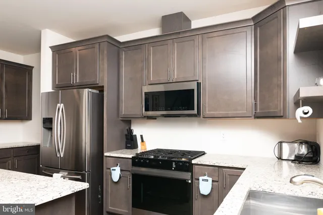 a kitchen with stainless steel appliances kitchen island granite countertop a refrigerator and a sink