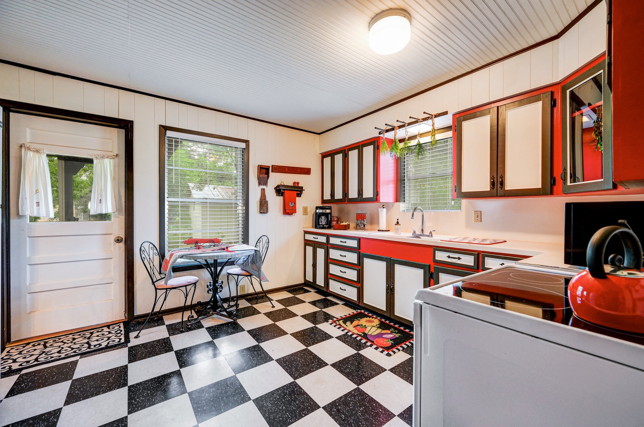 719 Elm Street Blanco, TX 78606 - Photo 14 of 25 Kitchen featuring checkerboard flooring, white paneled walls, and red and white cabinetry