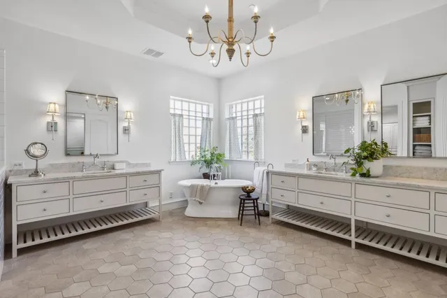 a bathroom with a double vanity sink a mirror a bathtub and window
