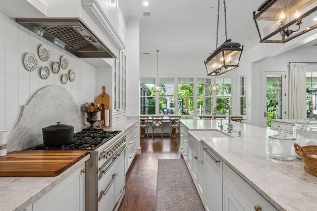 a kitchen with stainless steel appliances kitchen island granite countertop a table chairs and a view of living room